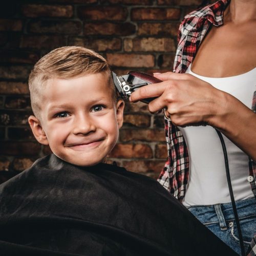 Cute preschool boy getting haircut.